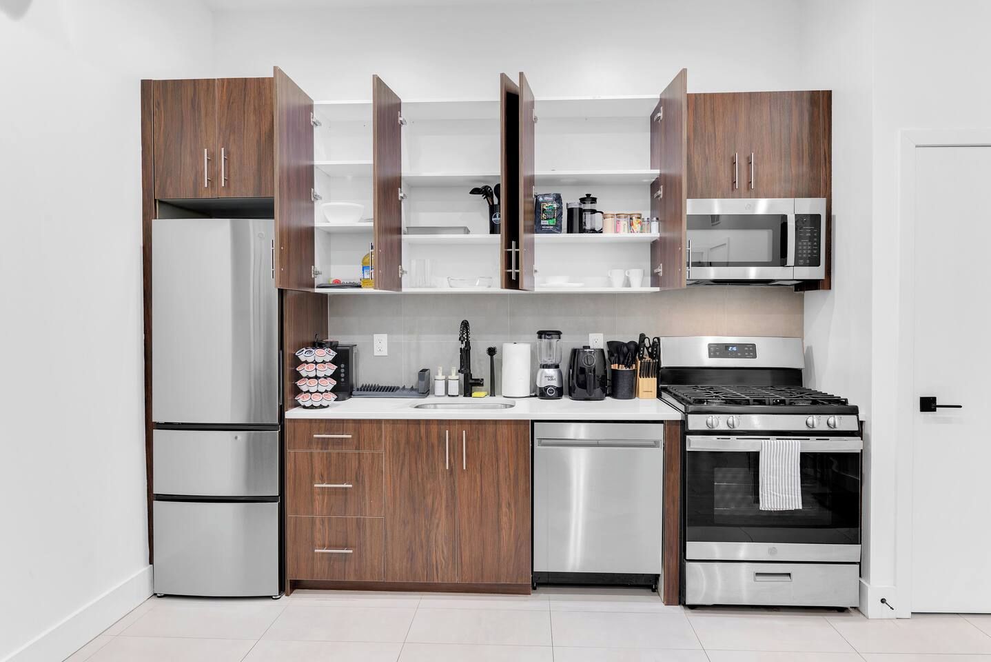 A modern kitchen with stainless steel appliances, wooden cabinets, and a white countertop.