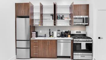 A modern kitchen with stainless steel appliances, wooden cabinets, and a white countertop.