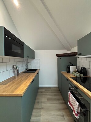 Eine kompakte Küche mit eingebautem Backofen, einer Spüle und einer Holzausziehtafel.
