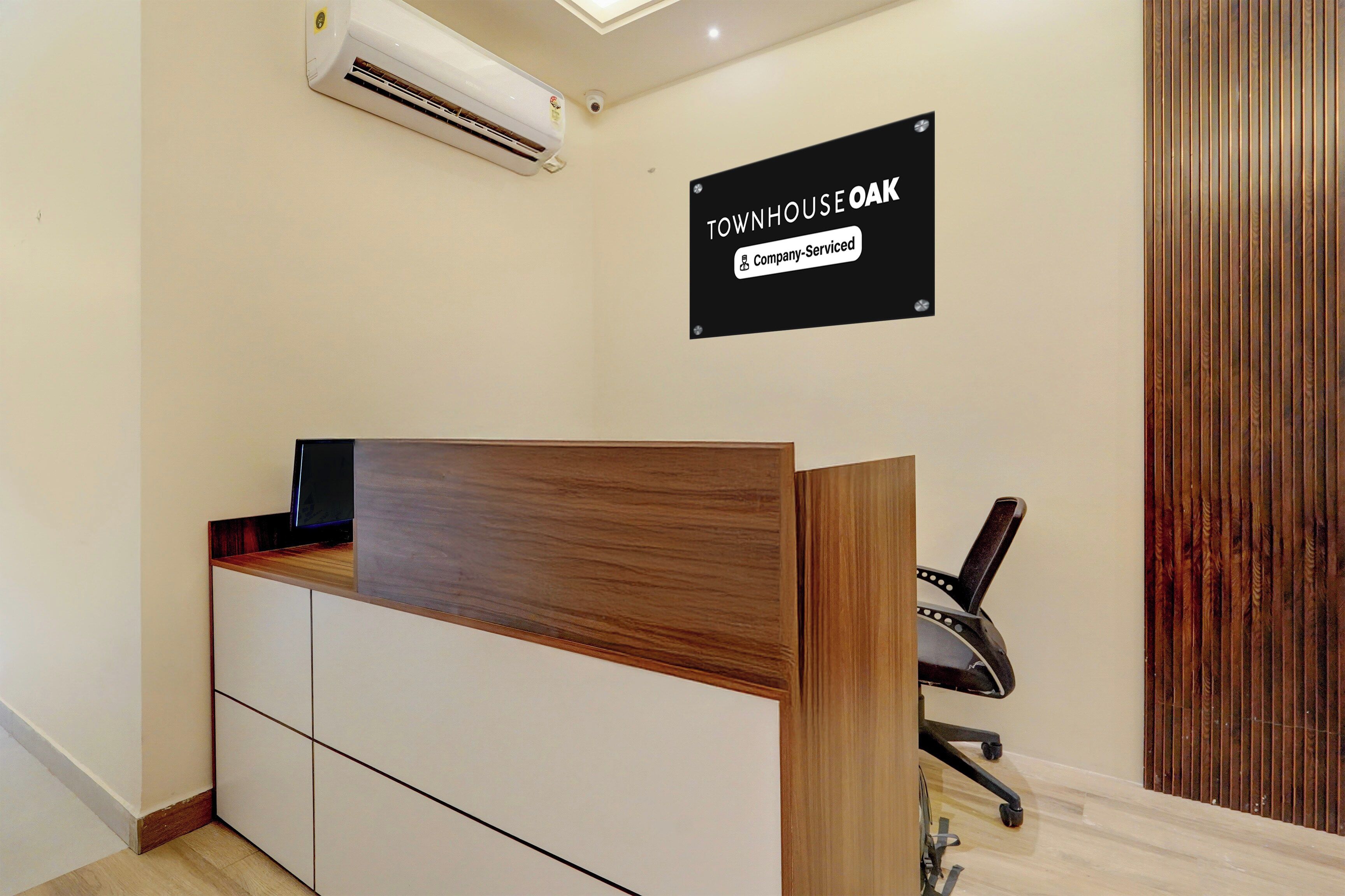 A reception desk with a company-serviced sign, a modern chair, and an air conditioning unit.