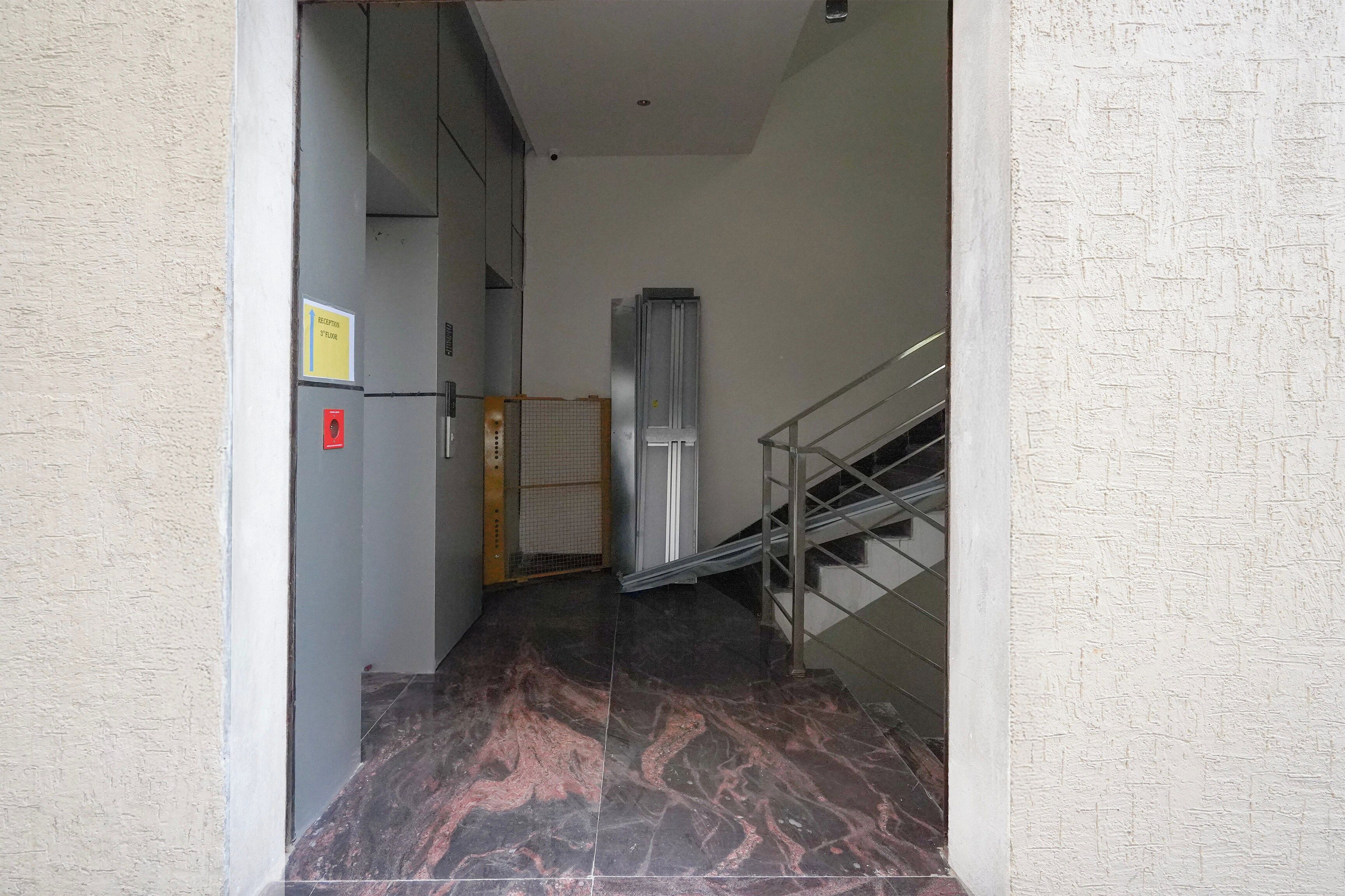 A hallway with a reception sign, a fire alarm, and a staircase.