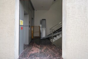 A hallway with a reception sign, a fire alarm, and a staircase. - Townhouse Oak Airport Ranchi (Ranchi)