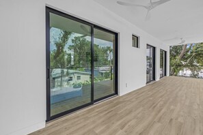 A corridor with large sliding glass doors leading to an outdoor area with a wooden deck. - Sarasota Coastal Retreat (Sarasota)