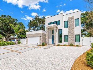 Een modern huis met twee verdiepingen, een stenen gevel, een garage en een oprit met grind.