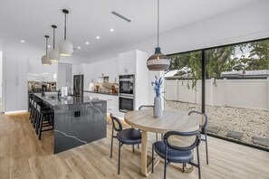 Een moderne keuken met een centraal eiland, een eetgedeelte met stoelen en uitzicht op de omgeving.