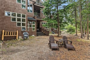 A cabin with a deck, outdoor seating, and a forested backdrop. - Beautiful apartment on the river, near shops and close to major skiing resorts. (Frisco)