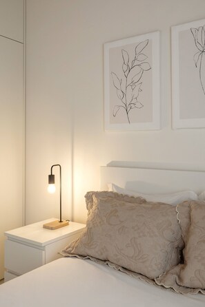 Ein Schlafzimmer mit einem Bett, einem Nachttisch, einer Lampe und Wandbildern.