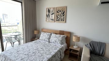 Habitació d'hotel amb un llit gran, un sofà, una taula petita i vistes a l'exterior.