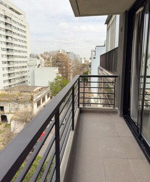 Ein Balkon mit Metallgeländer mit Blick auf ein Stadtbild und verschiedene Gebäude.