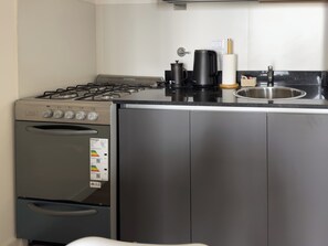 Eine kleine Küche mit Gasherd, Backofen und Kaffeemaschine.