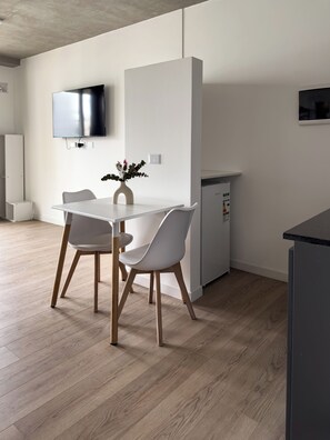 A modern kitchen with a dining table, chairs, a TV, and a refrigerator. - Wonderful studio with AC in vibrant Buenos Aires very close to Movistar Arena (Buenos Aires)