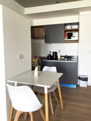 Una cocina moderna con una mesa y sillas blancas, un microondas y una cafetera.