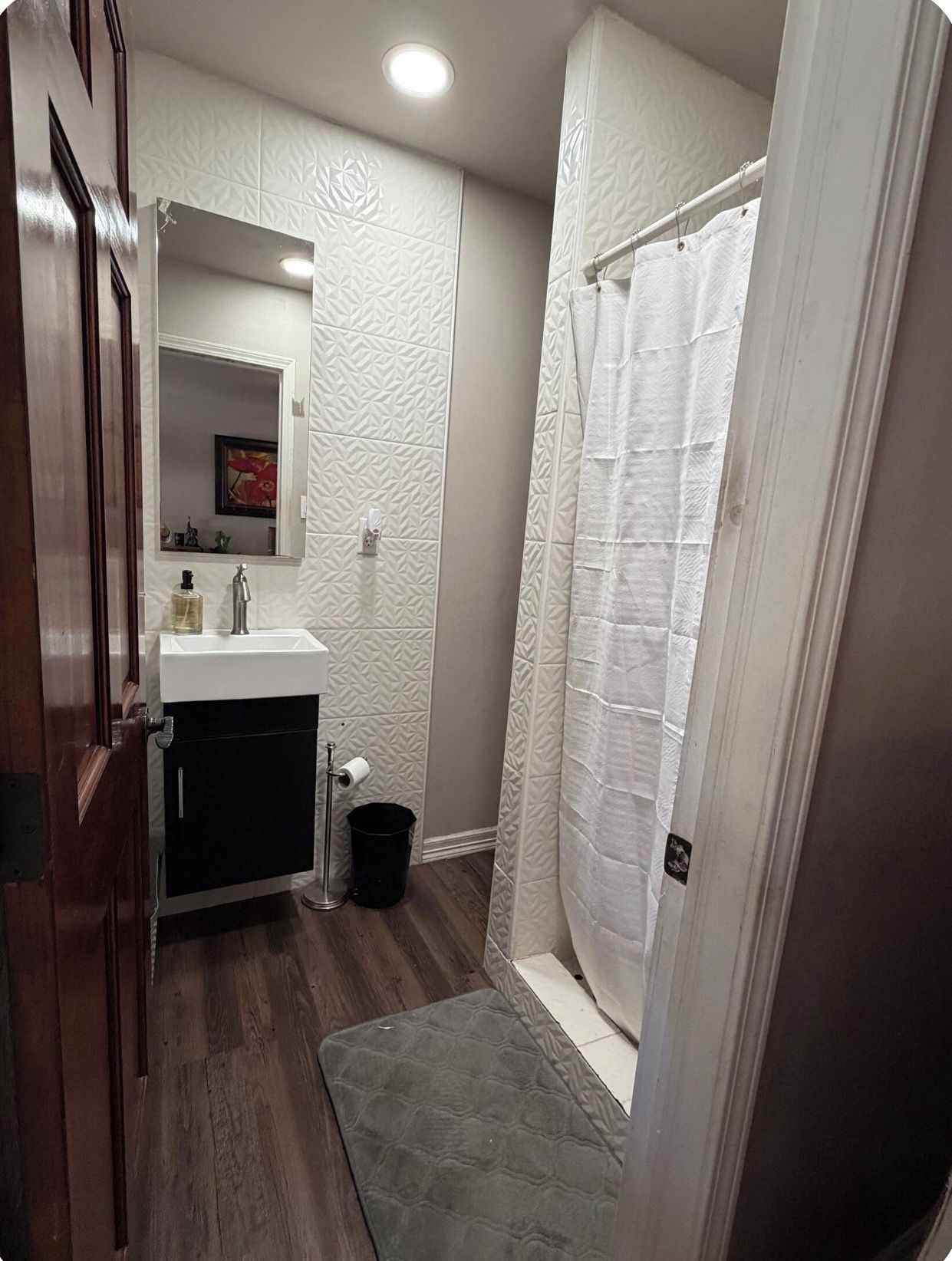 A bathroom with a white sink, mirror, and shower curtain.
