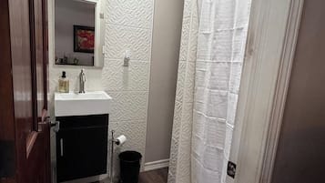 A bathroom with a white sink, mirror, and shower curtain.