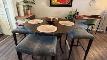 A round dining table with a central bowl, surrounded by four chairs with woven placemats.
