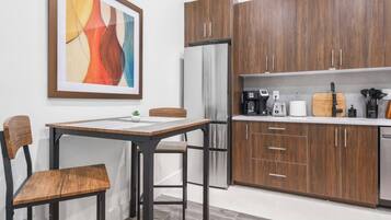 A modern kitchen with wooden cabinets, a stainless steel refrigerator, a coffee maker, and a toaster.