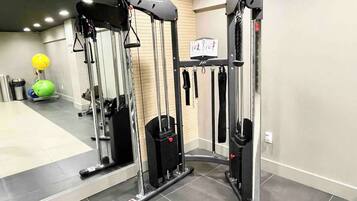 A gym with exercise equipment, a mirror, and a green exercise ball.