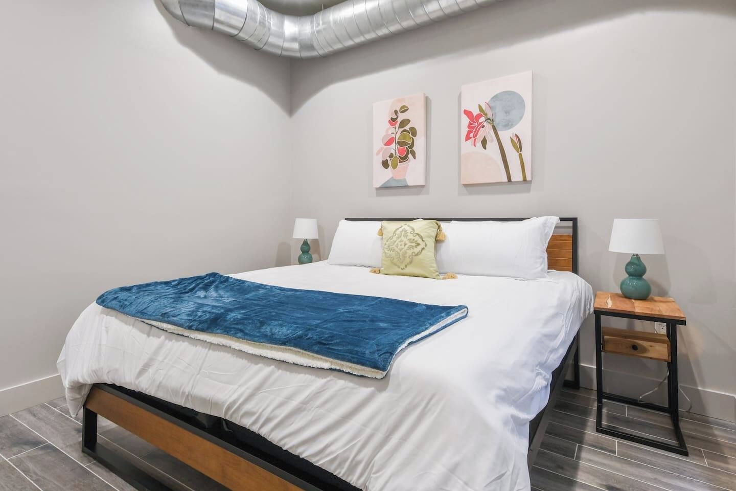A modern bedroom with a bed, two bedside tables, and wall art.