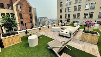 A rooftop terrace with outdoor seating, planters, and a view of the cityscape.