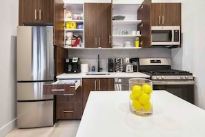 A modern kitchen with stainless steel appliances, wooden cabinets, and a white countertop. - Charming 1BR King Bed - Just 20 Minutes from NYC! (Newark)