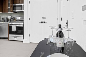 A modern kitchen with a dining table set for four, featuring a wine bottle and glasses. - 1BR King 20 min from NYC! 2 minutes to prudential (Newark)