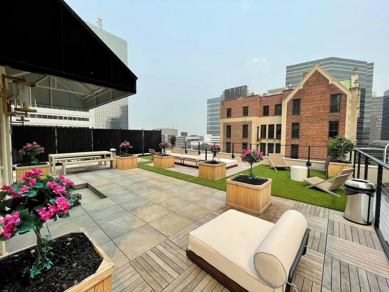 Eine Dachterrasse mit Außenbestuhlung, Blumenkästen und Blick auf umliegende Gebäude.
