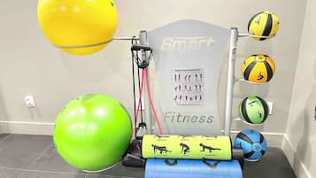 A fitness area with exercise equipment, including a resistance trainer, exercise balls, and a wall with fitness-related illustrations.