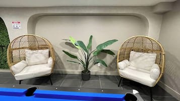 A pool area with two wicker chairs and a potted plant.