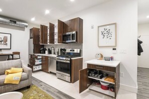 Eine moderne Küche mit Holzschränken, Edelstahlgeräten und einem Essbereich mit grauem Sofa.