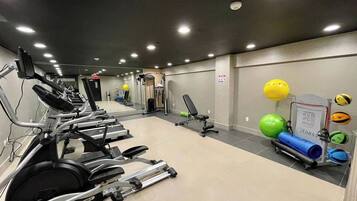 A gym with exercise equipment, including treadmills and stationary bikes, and a wall-mounted rack with exercise balls.