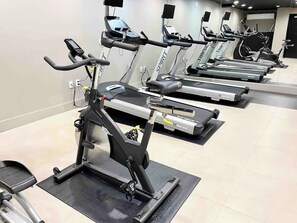 A row of stationary bikes in a gym with a mirrored wall. - 1BR Oasis, 20 Min NYC, 4 Min to Prudential Concert (Newark)