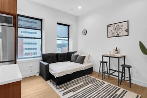 A modern bedroom with a bed, a small table, and a window. - 1BR Oasis, 20 Min NYC, 4 Min to Prudential Concert (Newark)