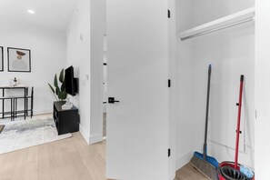 A modern interior with a dining area, a closed door, and cleaning supplies. - Monthly friendly Lux 1BR 20 Min NYC 4 min to Prud (Newark)