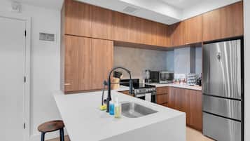 A modern kitchen with wooden cabinets, a stainless steel refrigerator, a built-in oven, and a sink with a faucet.