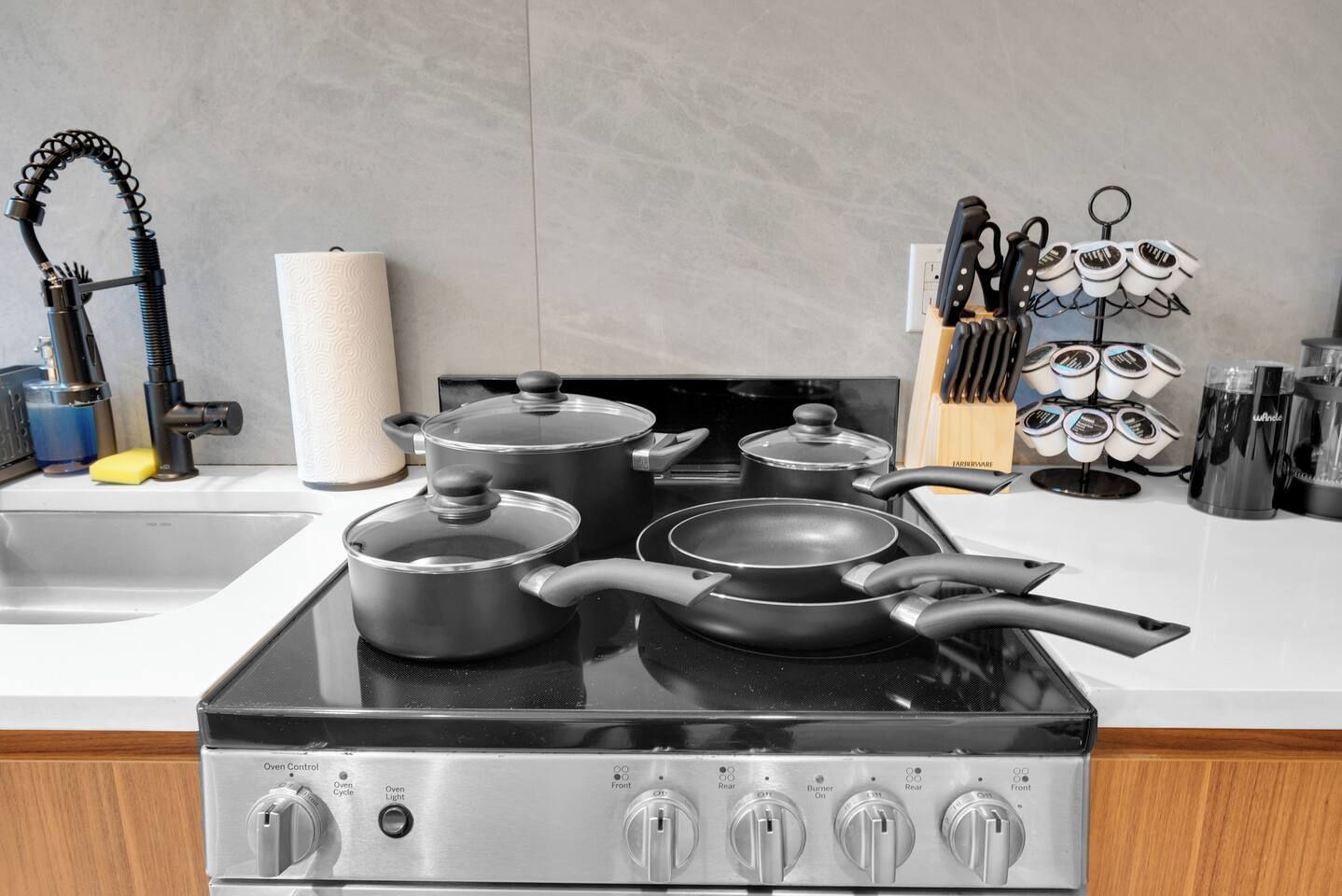 A kitchen with a stove, pots, pans, a knife rack, and a paper towel holder.