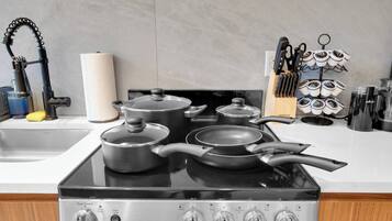 A kitchen with a stove, pots, pans, a knife rack, and a paper towel holder.
