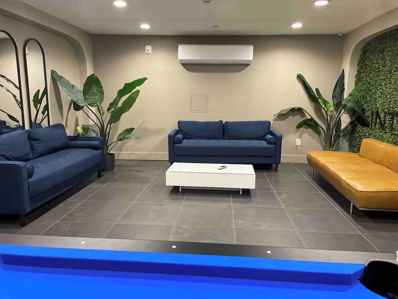 A modern lounge area with two sofas, a coffee table, and potted plants.