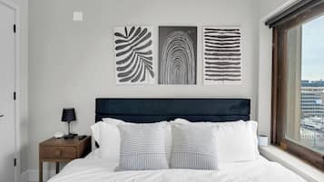 Un dormitorio con una cama, una mesita de noche, una lámpara y tres cuadros en la pared.