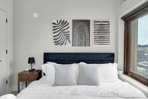 Ein Schlafzimmer mit einem Bett, einem Nachttisch, einer Lampe und drei Wandbildern.