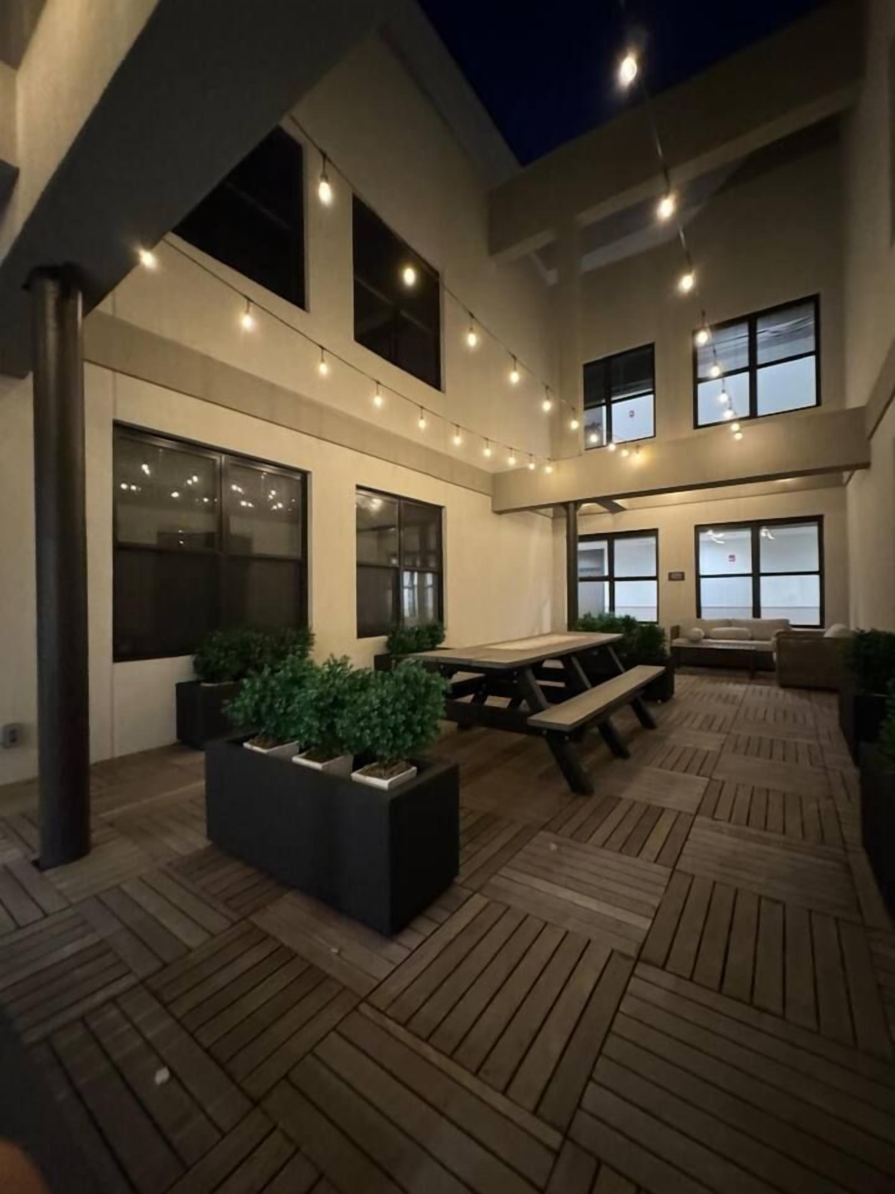 An outdoor patio area with a wooden deck, seating arrangements, and potted plants.