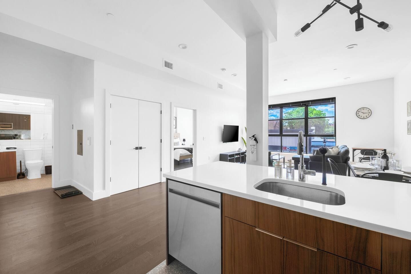 A modern kitchen with white cabinetry, a built-in dishwasher, and a large island with a sink.