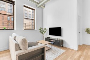 Een moderne woonkamer met een bank, televisie en een kleine tafel.