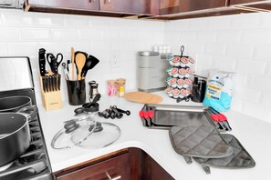 A kitchen with a stove, pots, a coffee maker, a kettle, a knife block, a cutting board, a muffin tray, a muffin tin, a muffin rack, a muffin box, a muffin bag, and a muffin box with a label. - 2BR 20 min to NYC! Stylish Fun Cozy & Spotless (Newark)