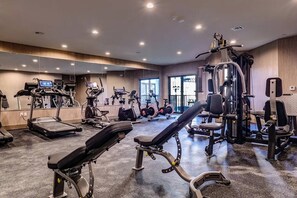 Ein Fitnessstudio mit verschiedenen Trainingsgeräten, darunter Laufbänder, Crosstrainer und Kraftgeräte.