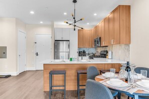 Eine moderne Küche mit Holzausstattung, einem Edelstahlkühlschrank und einer zentralen Kochinsel mit Barhocker.