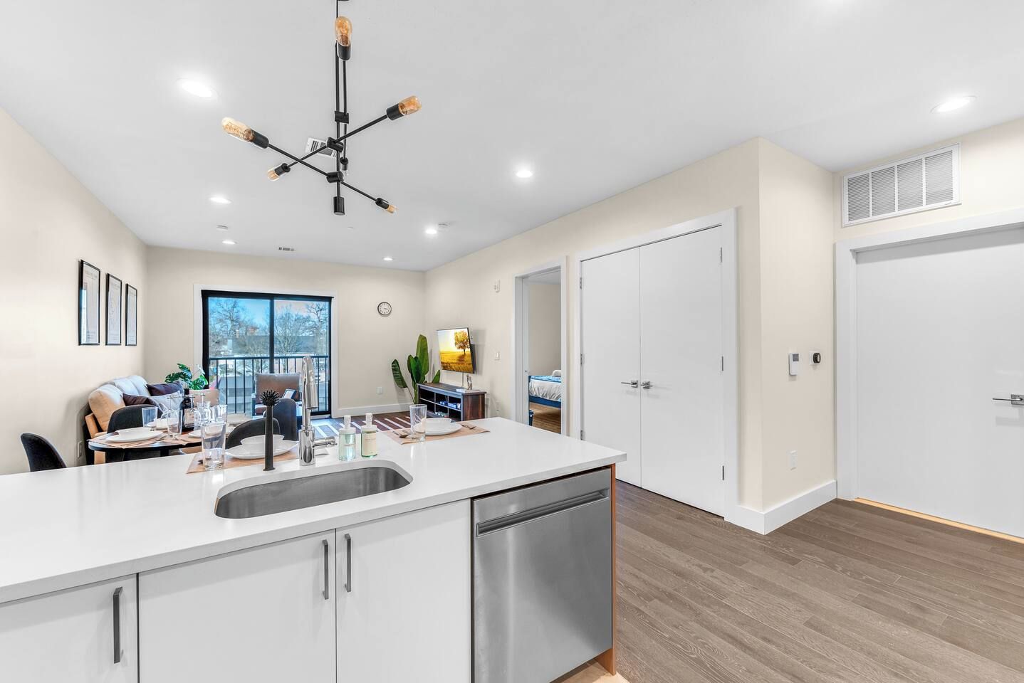A modern kitchen with a large island, stainless steel appliances, and a pendant light fixture.
