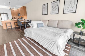 Een moderne slaapkamer met een groot bed, een eethoek en een kitchenette.