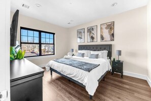 A bedroom with a large bed, a nightstand, a desk, and a window with a view of buildings. - Lux! Gym! King bed-Free Parking Long Term Friendly (Plainfield)