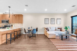 A modern kitchen with a dining area, a sofa set, and a large window. - Lux! Gym! King bed-Free Parking Long Term Friendly (Plainfield)