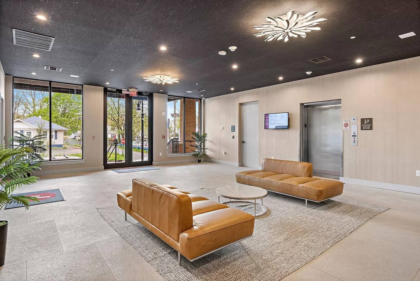 A modern waiting area with leather sofas, a coffee table, and a large window providing a view of the outside.